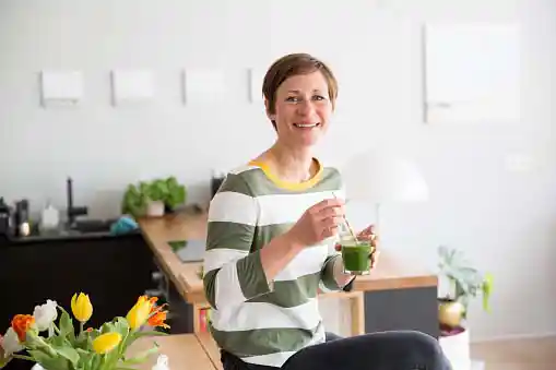 fit woman smiling and holding glass of smoothie